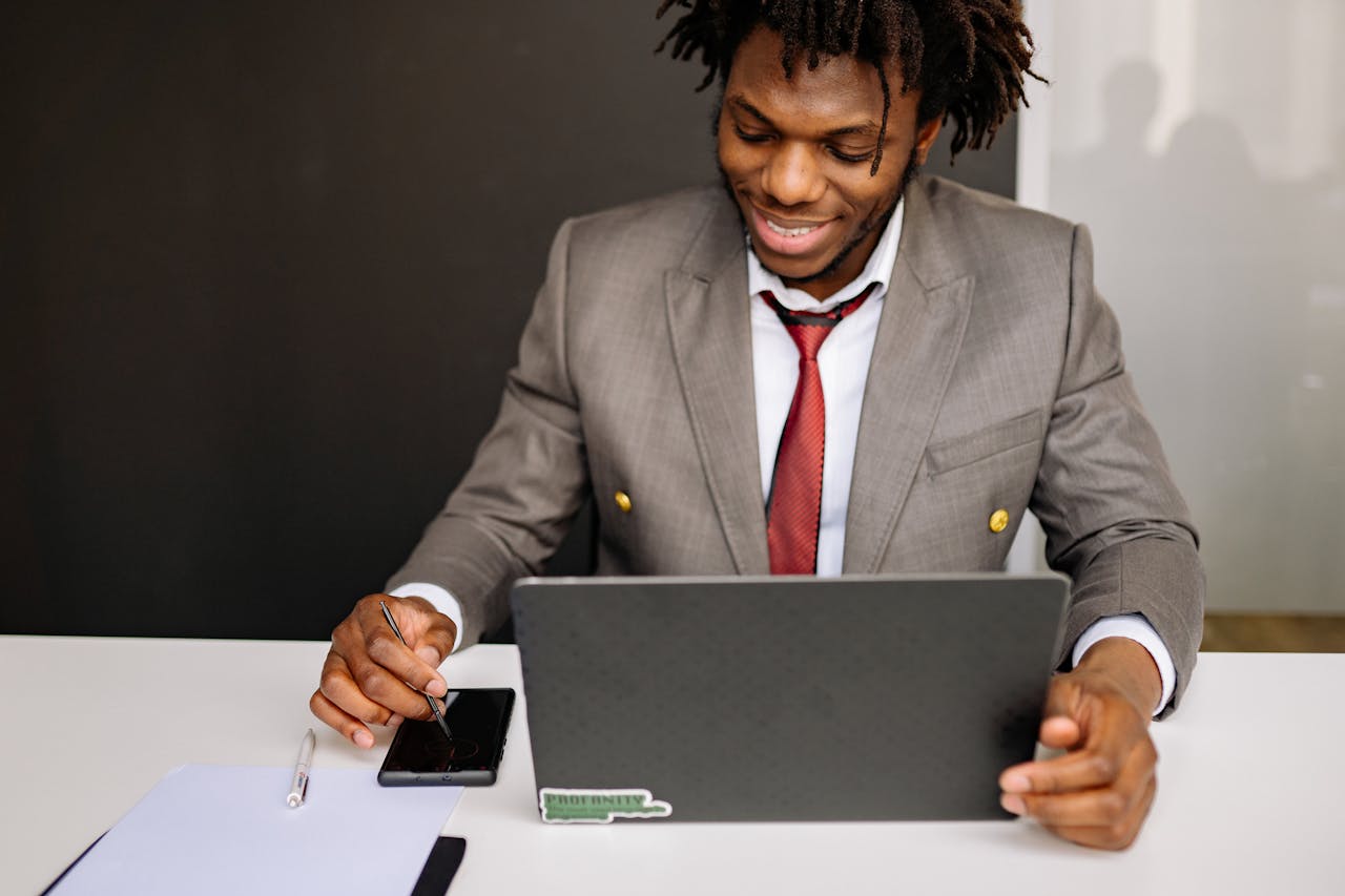 Young African American businessman working on laptop in modern office setting.